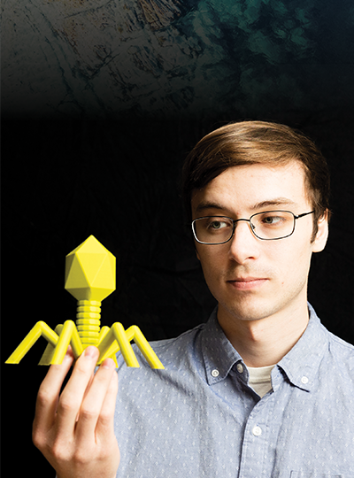Scientist holds 3D printed phage over a natural background.