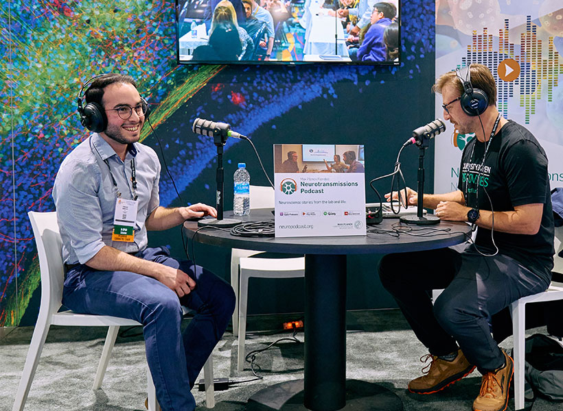 Two men sitting at a booth wearing headphones.