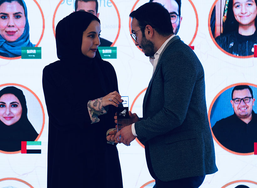 Woman hands man an award on stage.