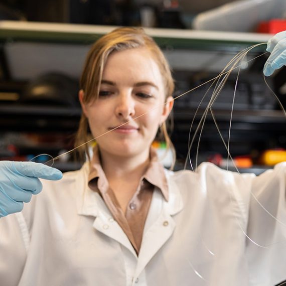 A scientists stretches fibers in a lab.
