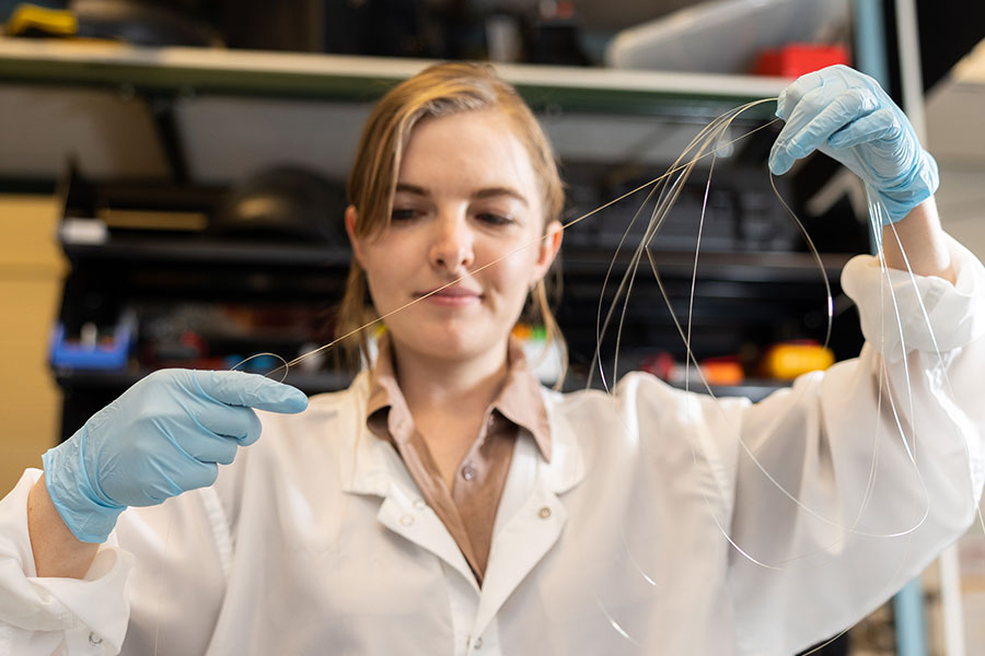 A scientists stretches fibers in a lab.