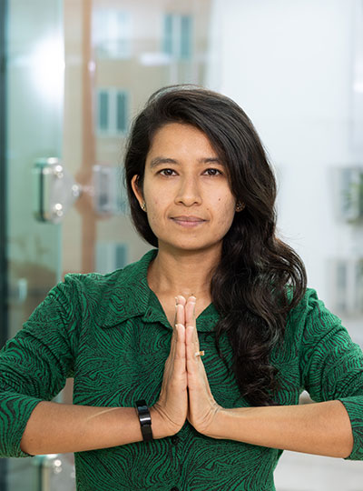 Woman clasping hands in a yoga pose, looking directly into the camera. 