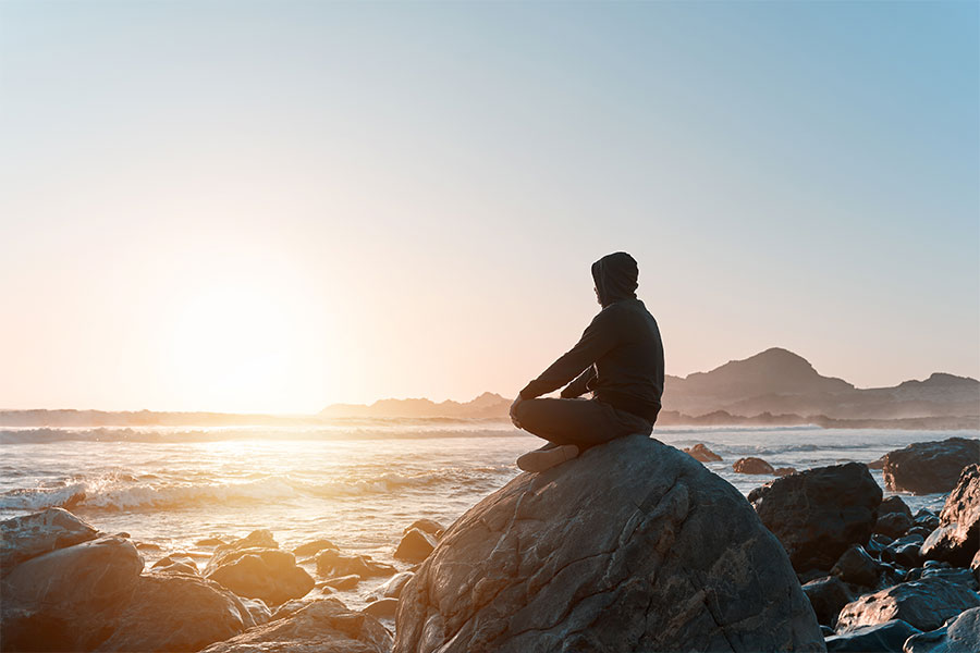 person sitting on rock looking out at the ocean