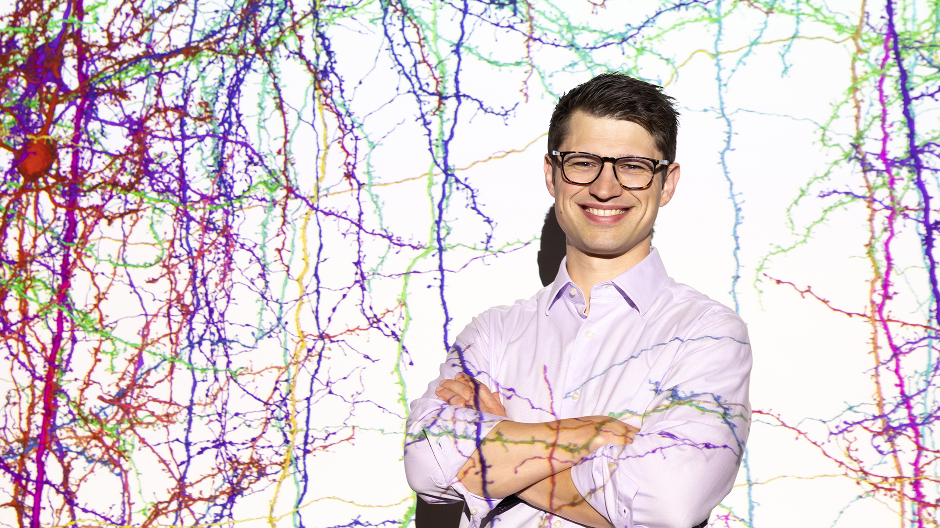 Sven Dorkenwald stands in front of a projected image of the connectome.