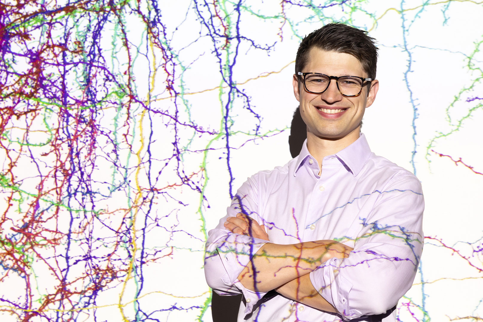 Sven Dorkenwald stands before a projection of the mouse connectome.