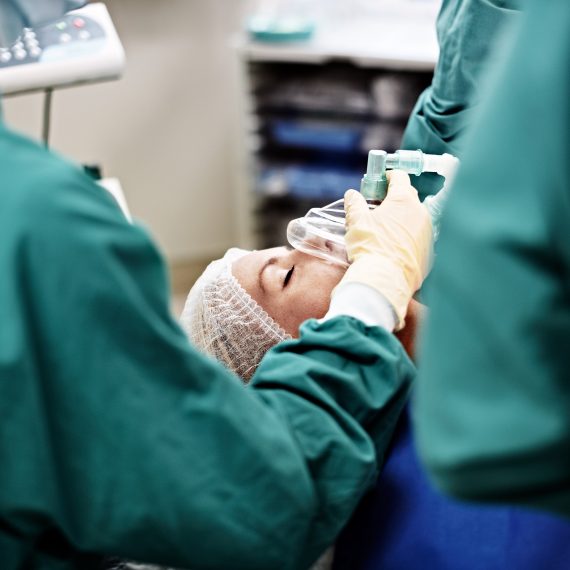 A medical team administers anesthesia to a patient in an operating room.